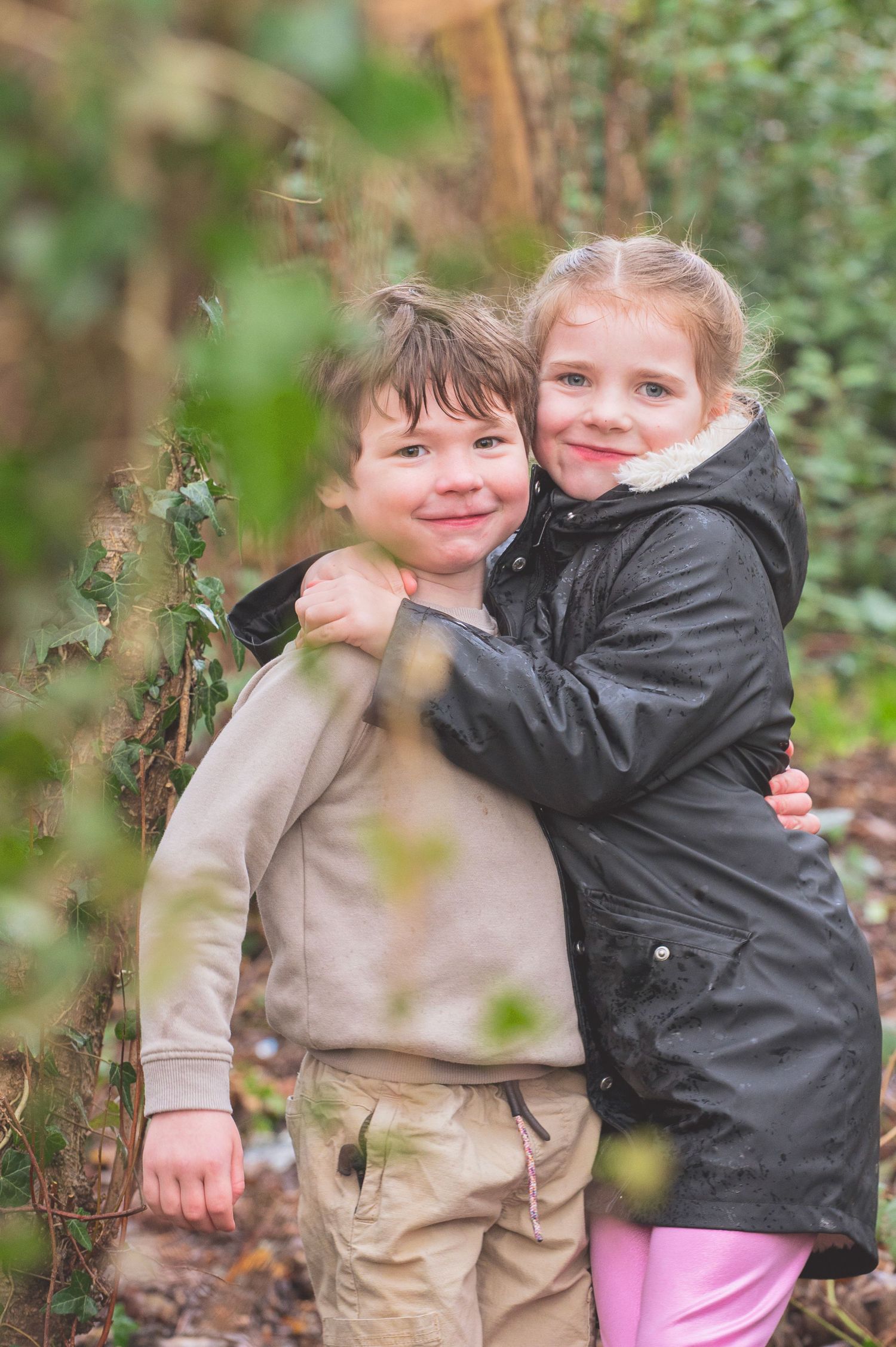 Two children share a sweet hug while playing outdoors in autumn foliage.