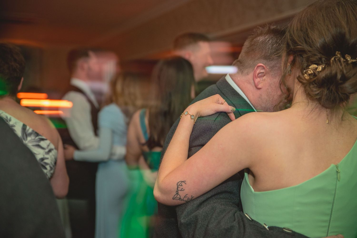 Wedding couple shares a tender kiss during a festive green-themed celebration.
