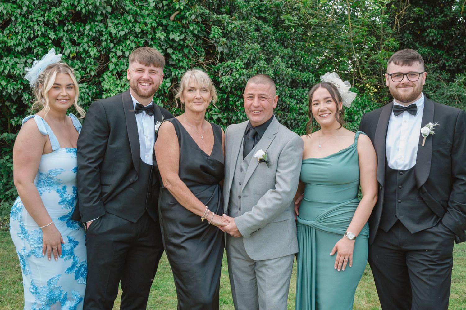 Elegantly dressed family of six posing together outdoors at a formal event, wearing black tie and formal gowns.