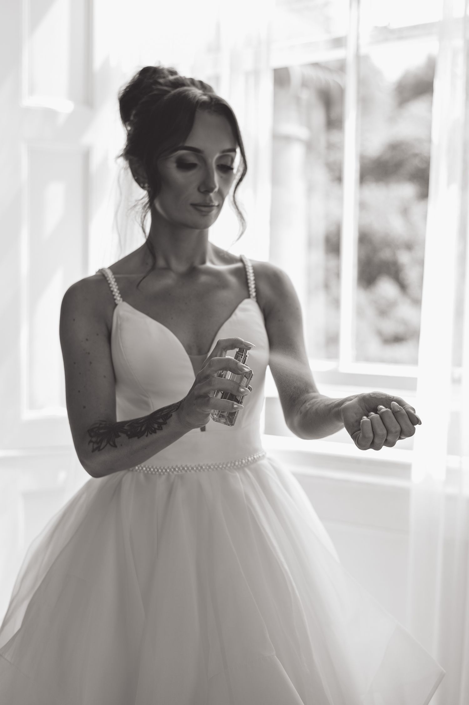 Black and white portrait of bride in white dress with visible arm tattoos.