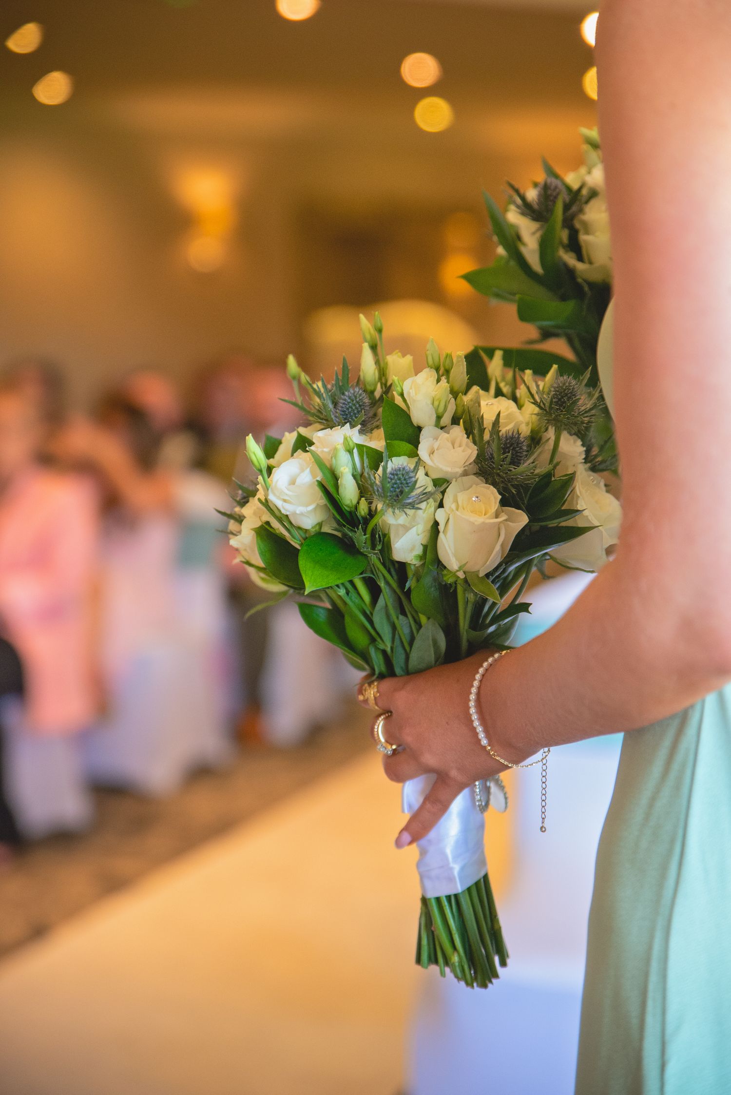 Bridesmaids holding elegant white and green floral bouquets at wedding ceremony.