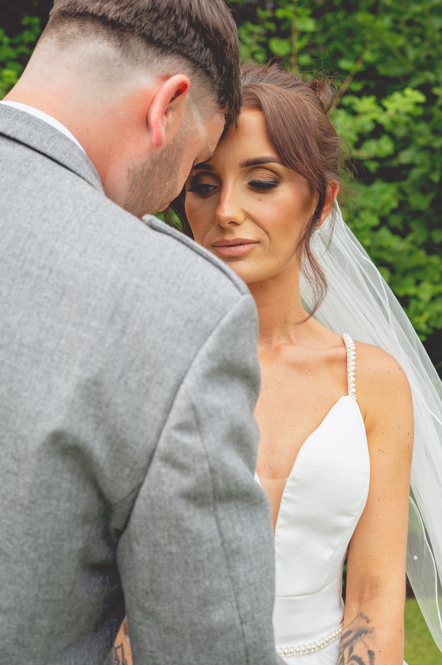Close-up wedding portraits showing intimate moments against green garden background.