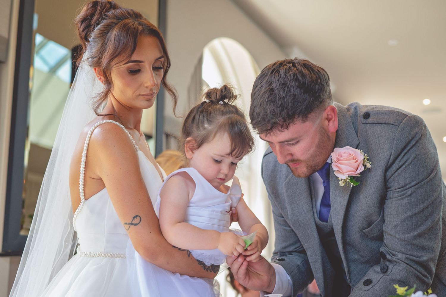 A tender family moment at a wedding with a small child between the couple.