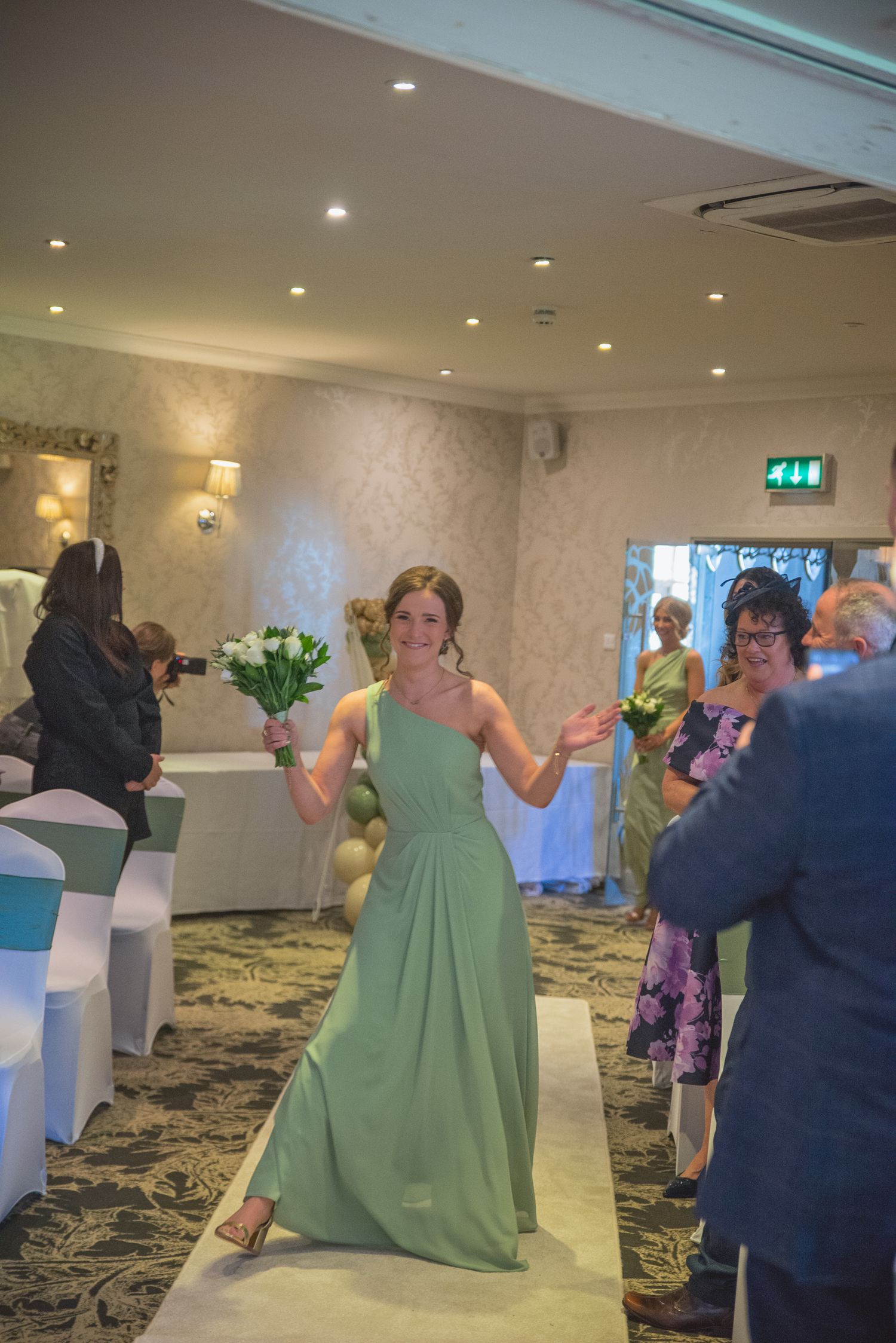 Wedding reception venue with guests dancing and mingling in a carpeted banquet hall.