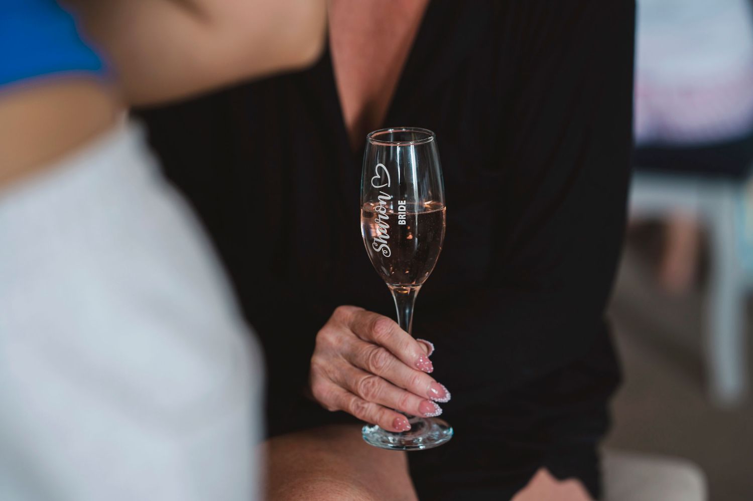 Close-up of a hand holding an elegant champagne flute at a wedding celebration.