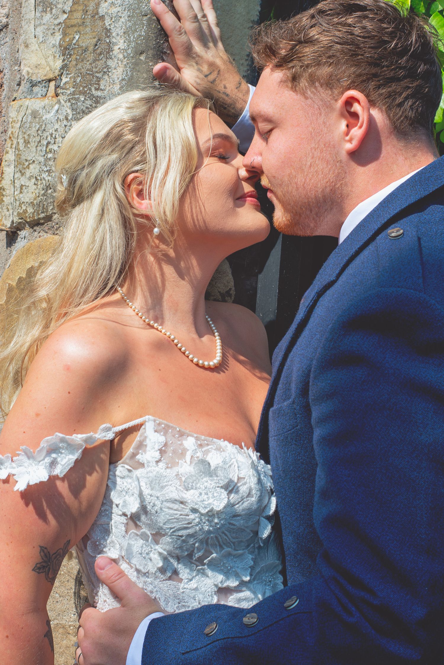 Romantic outdoor wedding portraits against a stone wall background.