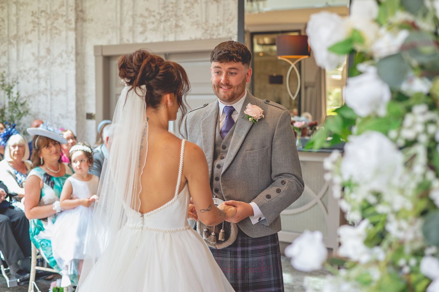 A wedding ceremony under a floral arch with the couple exchanging vows.