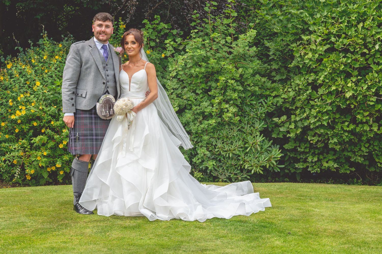 Romantic wedding portraits taken in a vibrant summer garden setting.