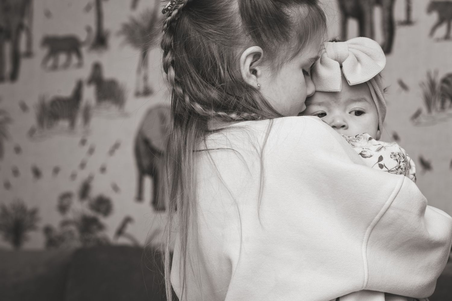 A series of black and white photos showing tender moments between a parent and baby in soft, intimate lighting.
