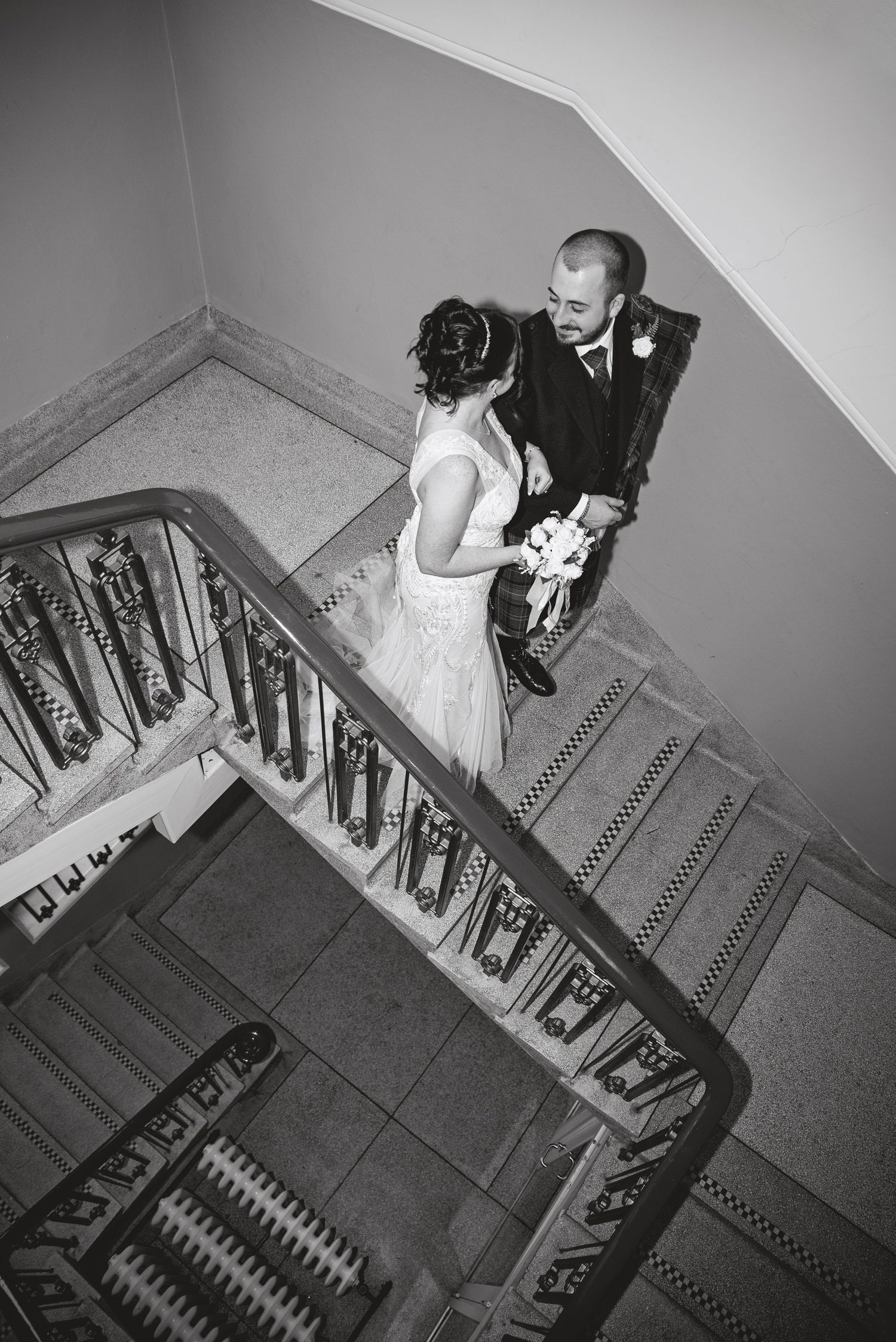 Black and white photo of couple meeting on elegant vintage staircase.