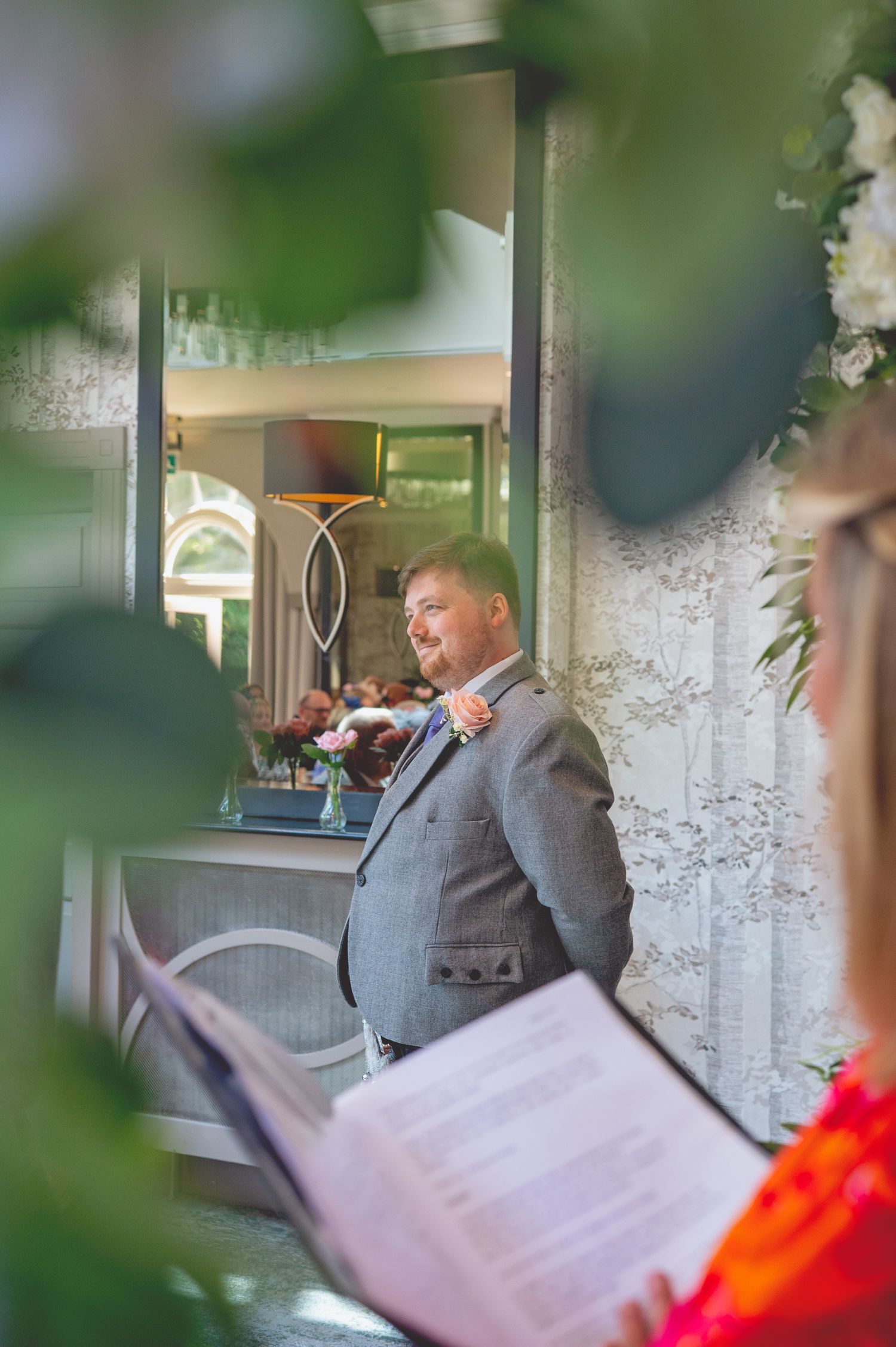 A speaker in traditional Scottish attire addresses guests during a wedding celebration.