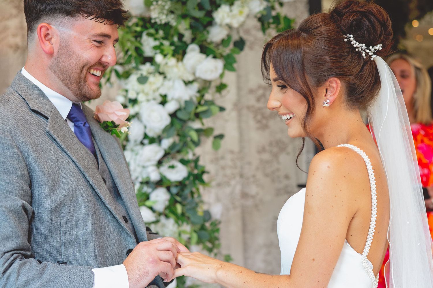 Romantic wedding moment captured under an archway decorated with white flowers.