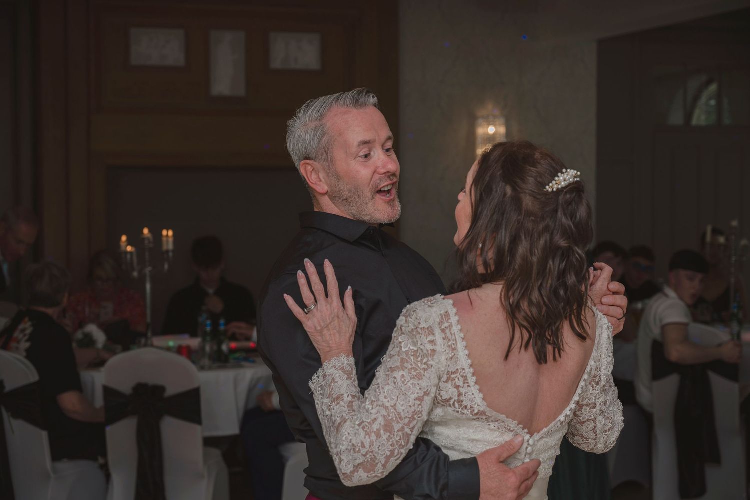 Bride and groom share their first dance in an elegant candlelit wedding reception hall.