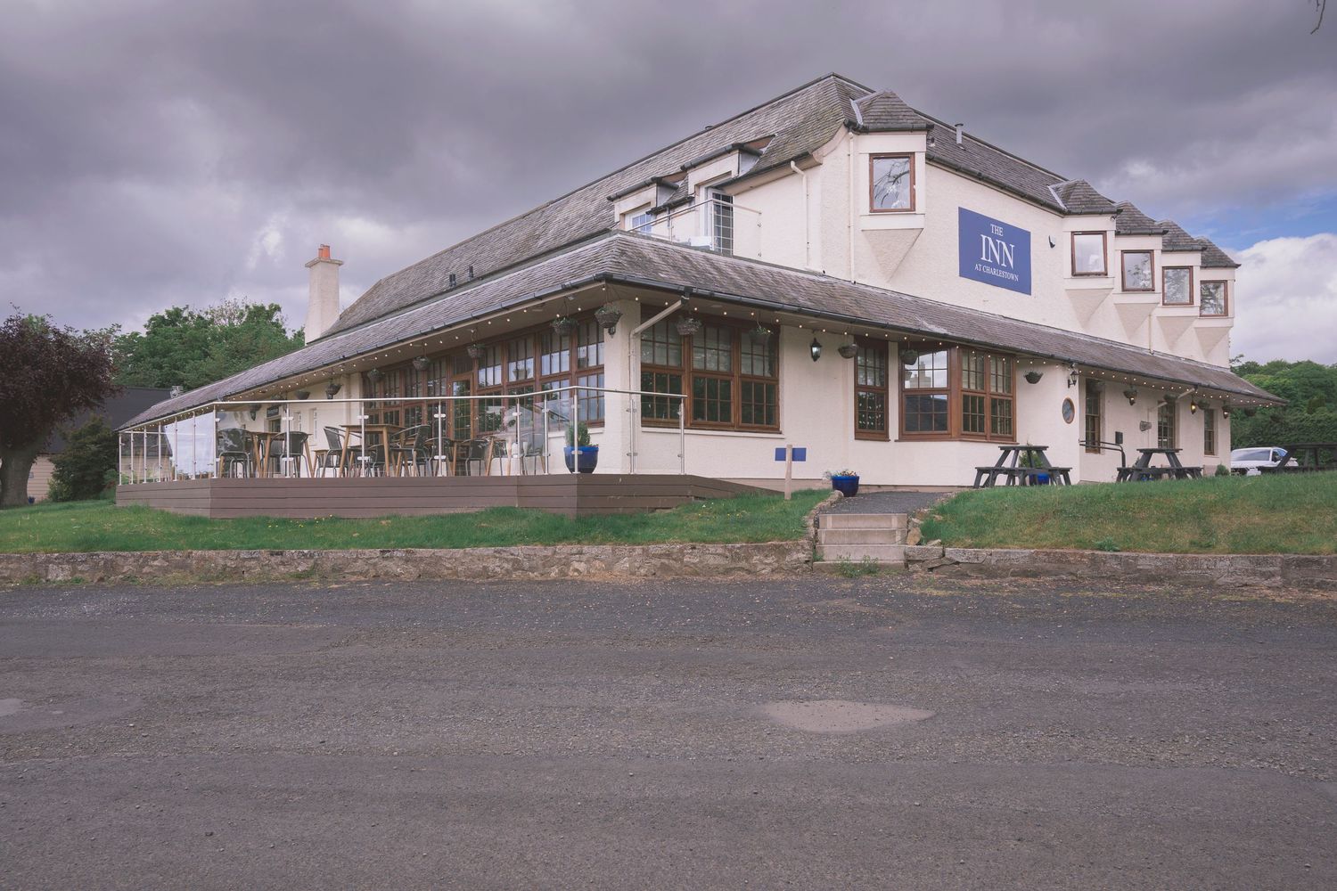 A large white roadside inn building with a glass-fronted extension under a cloudy sky.