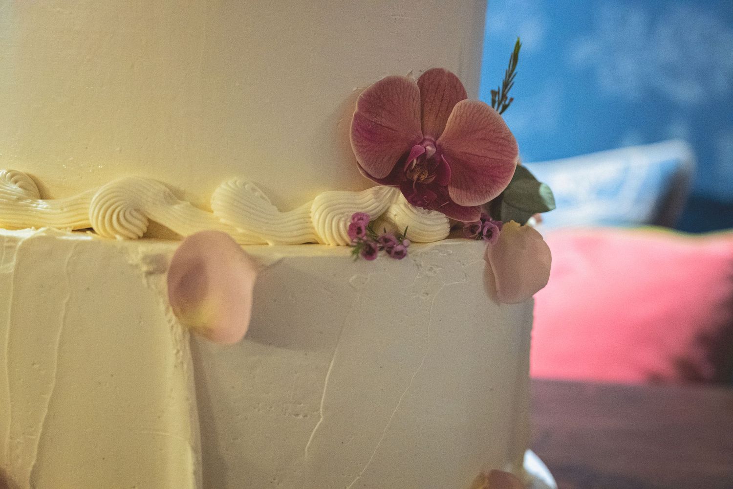 Elegant white wedding cake decorated with pink orchid and delicate sugar flowers closeup.