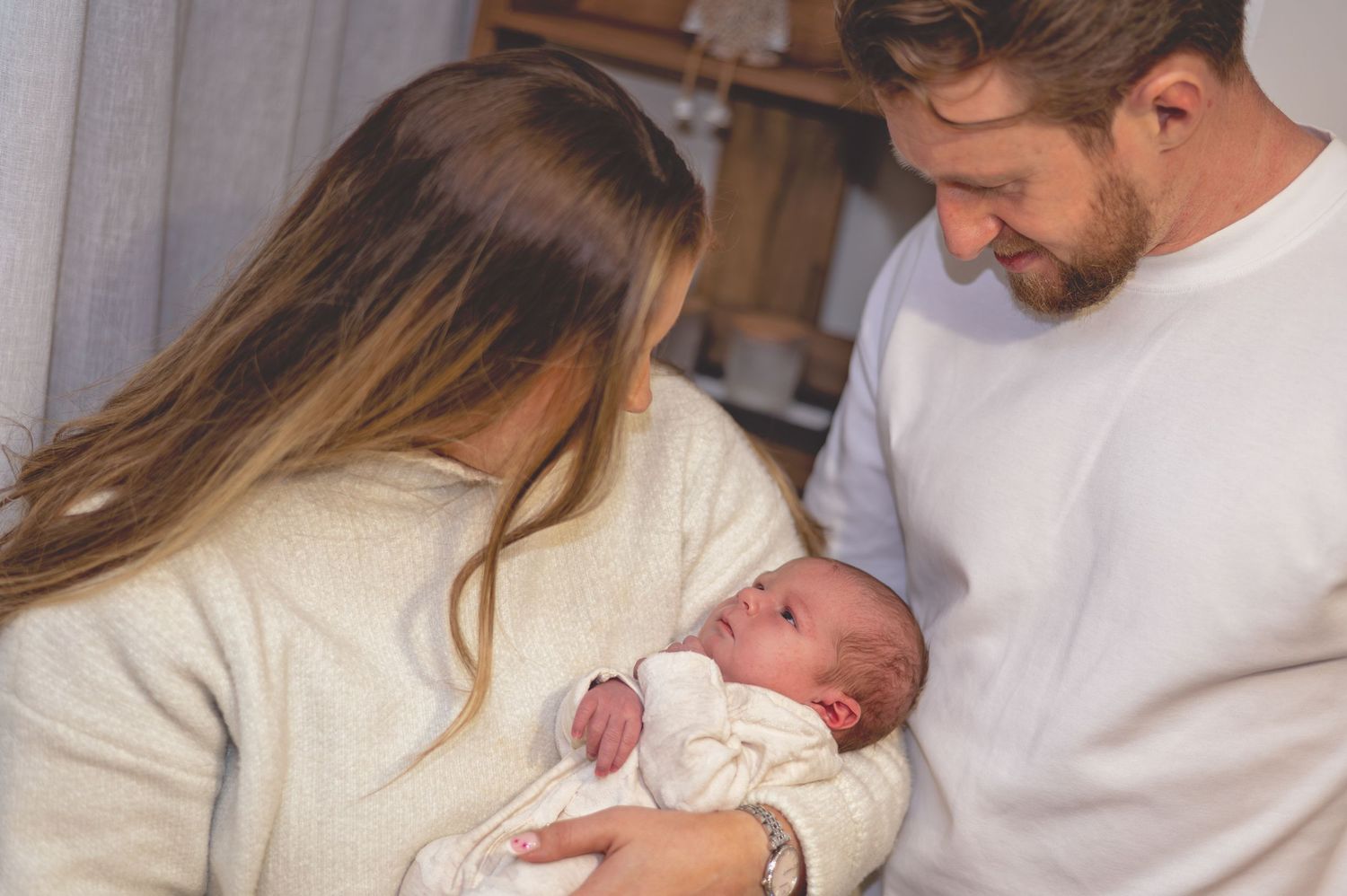 A series of tender moments showing a parent holding and bonding with their newborn baby in a bright indoor setting.