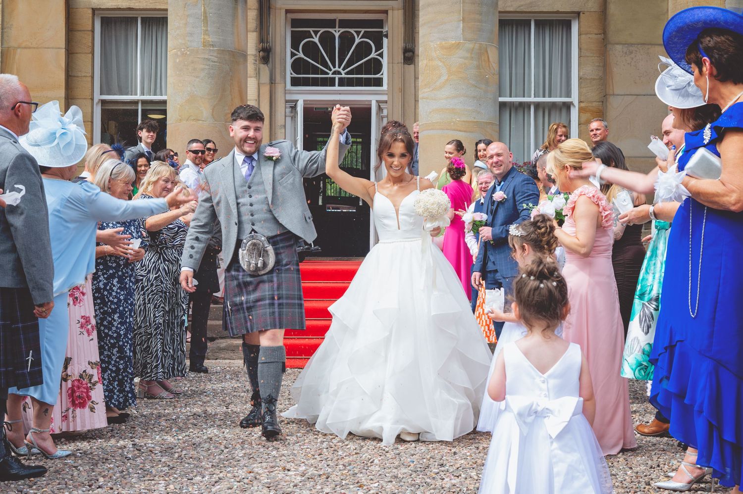 Guests line the steps of a stone building for wedding celebrations.