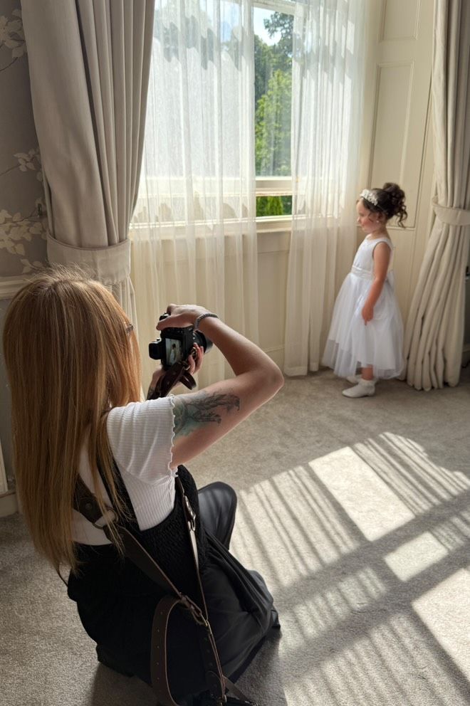 Behind-the-scenes wedding photography session in bright sunlit room with flowing curtains.