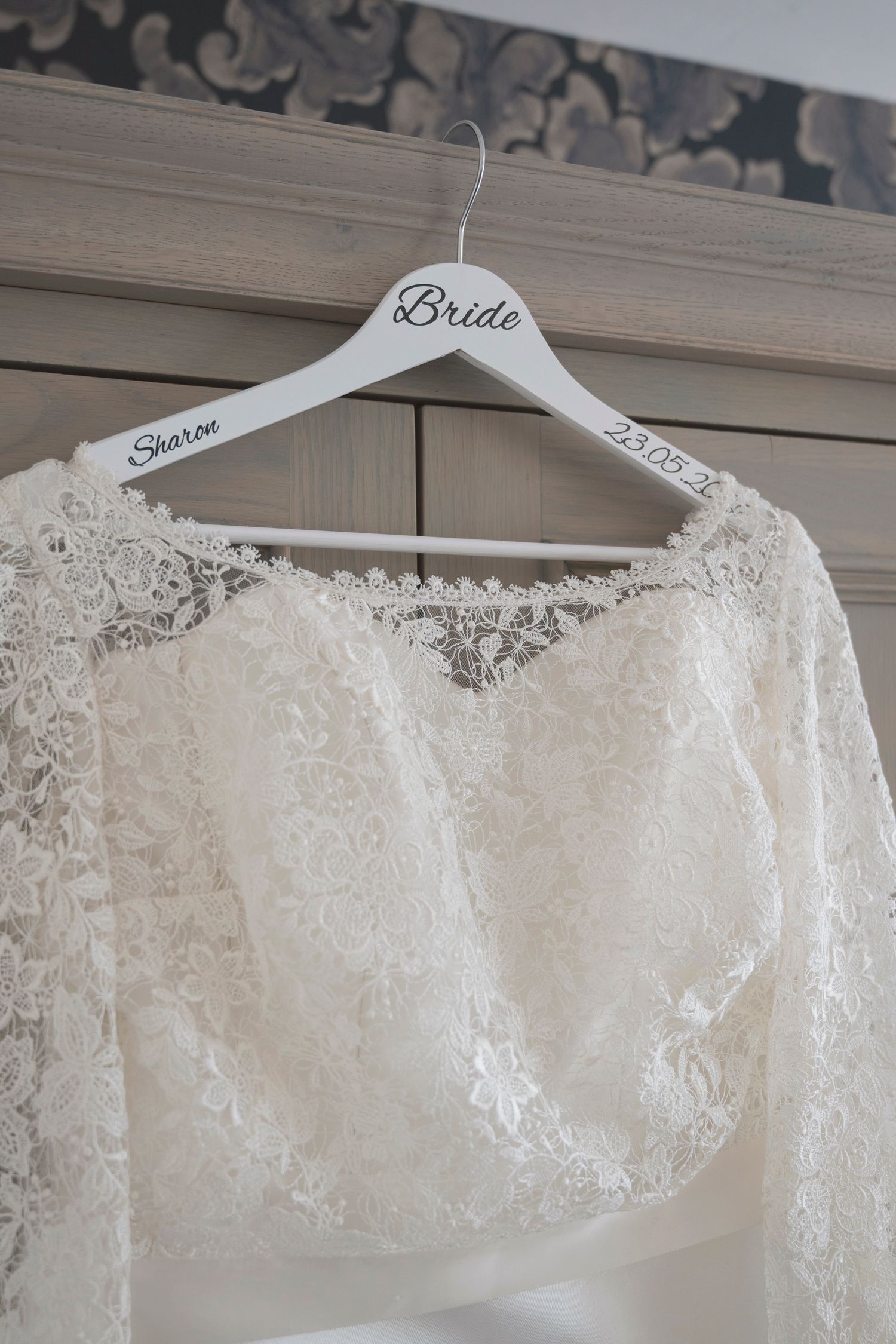 White lace bridal bolero jacket on a personalized bride hanger with name Sharon and wedding date 23.08.2x.