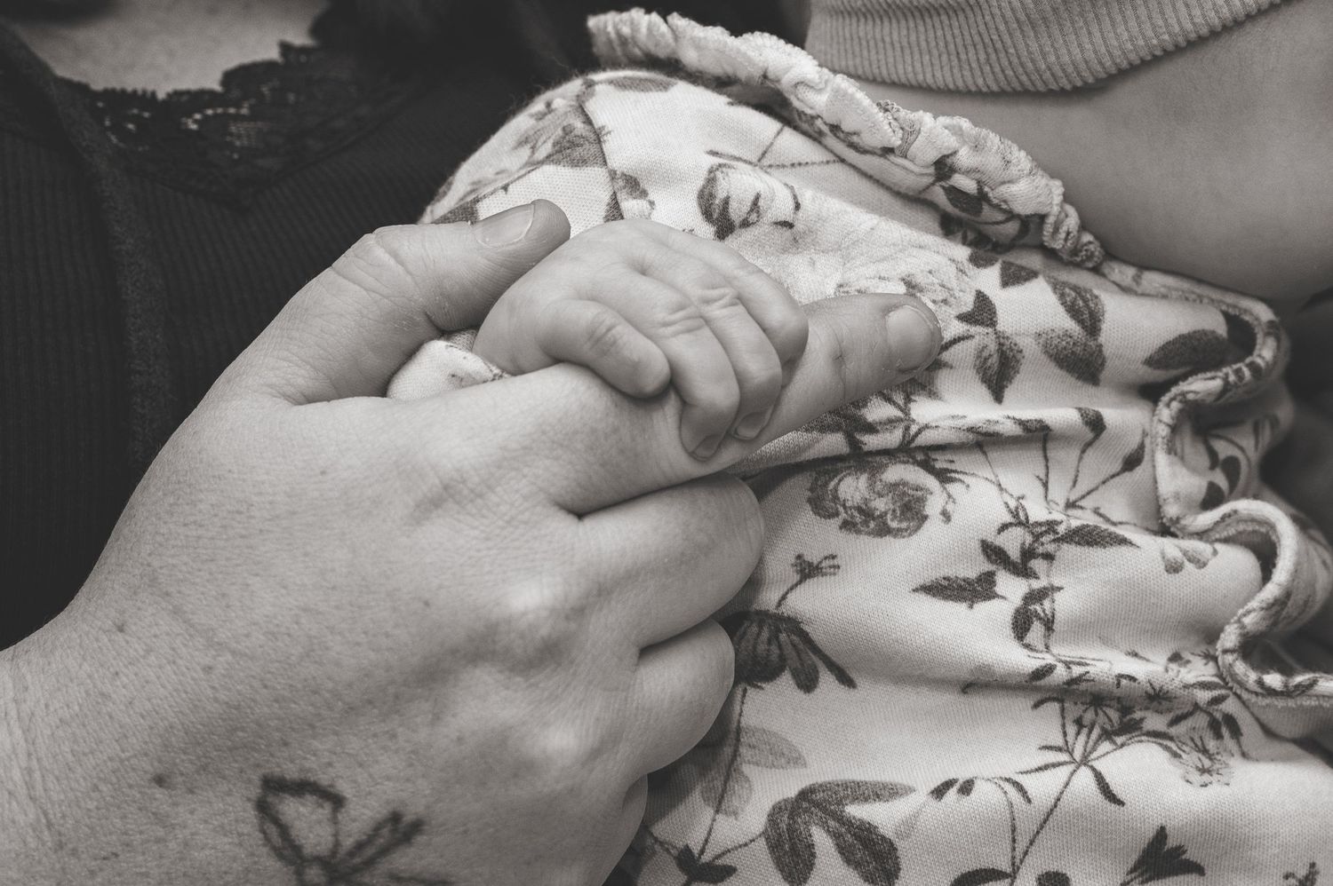 A series of black and white close-up photographs showing hands gently touching delicate floral fabric patterns.
