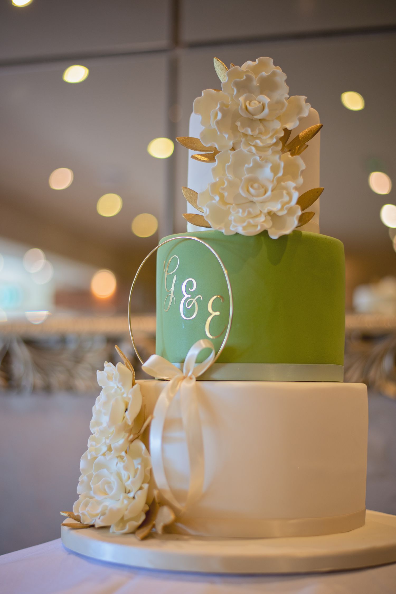 Elegant two-tier wedding cake in mint green and white with floral decorations.