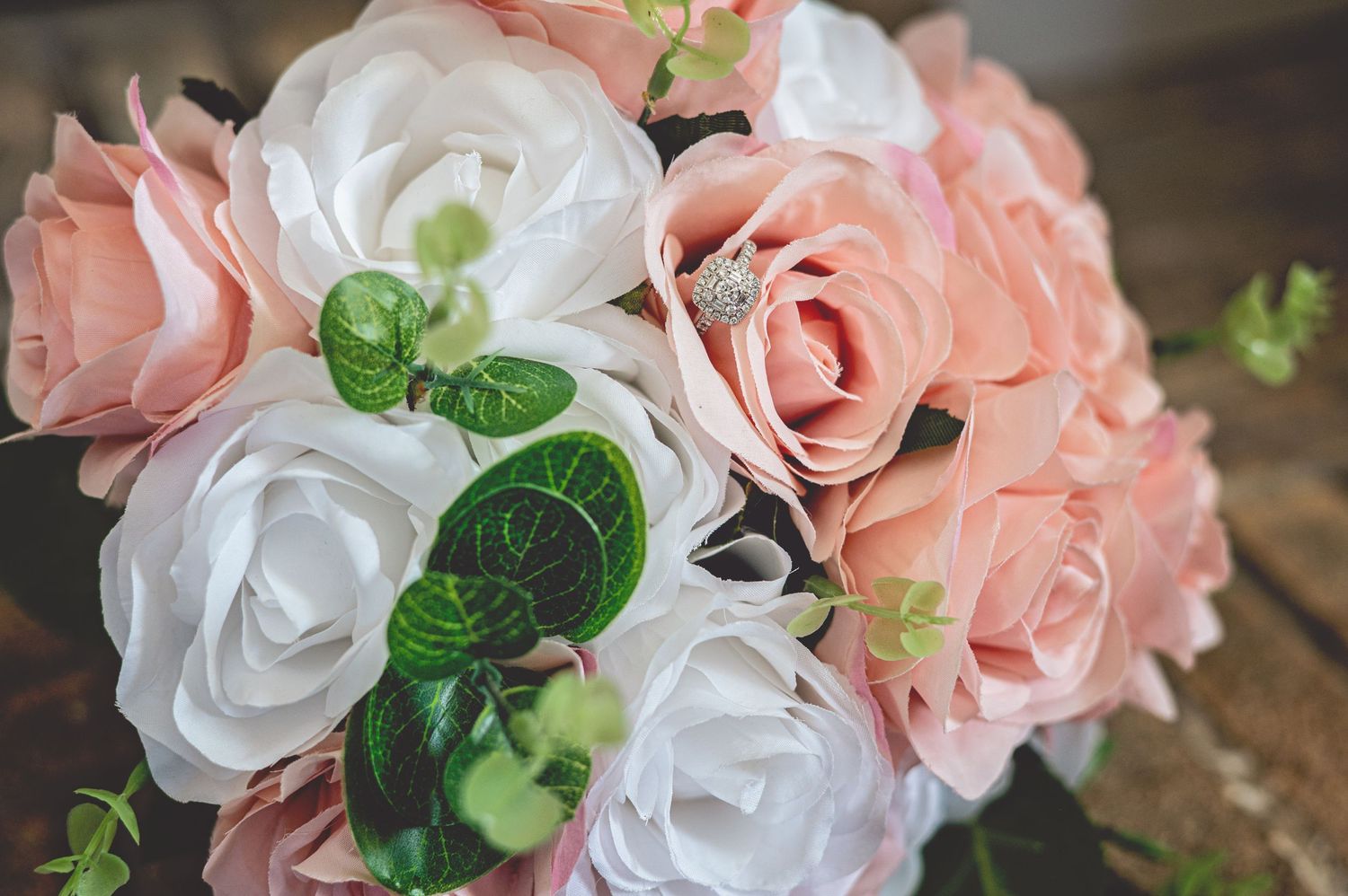 Wedding bouquet with pink and white roses featuring decorative green accents.