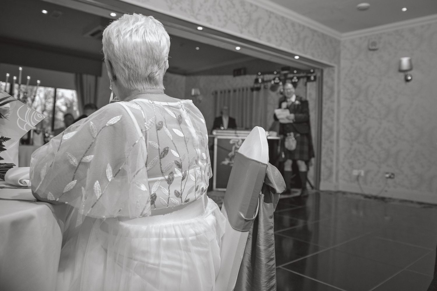 A person in a white dress stands near a decorated wedding venue.