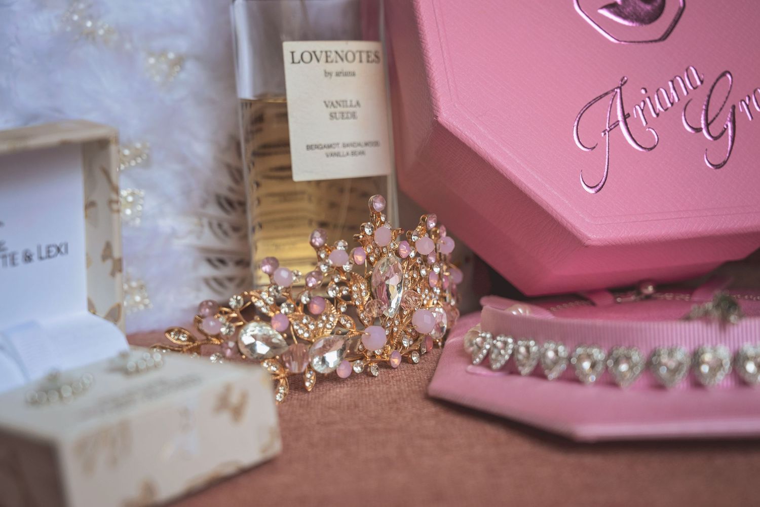 Gold rhinestone bridal crown and jewelry near pink Ariana Grande box and Lovenotes vanilla musk perfume.