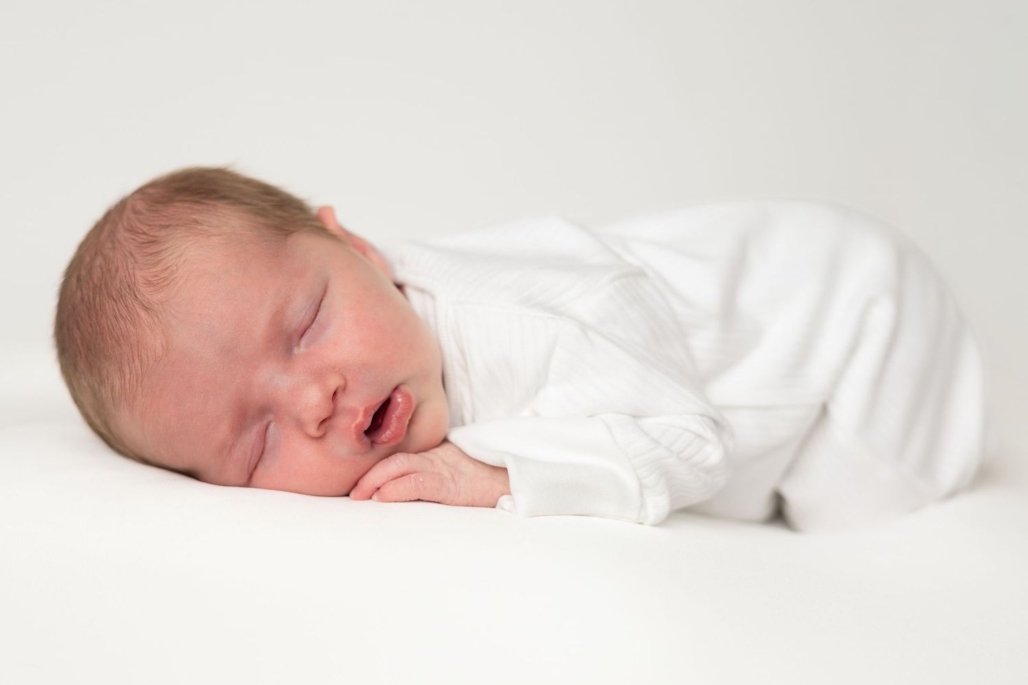 Newborn baby asleep on belly, wearing a white baby grow, Wicklow newborn photography session