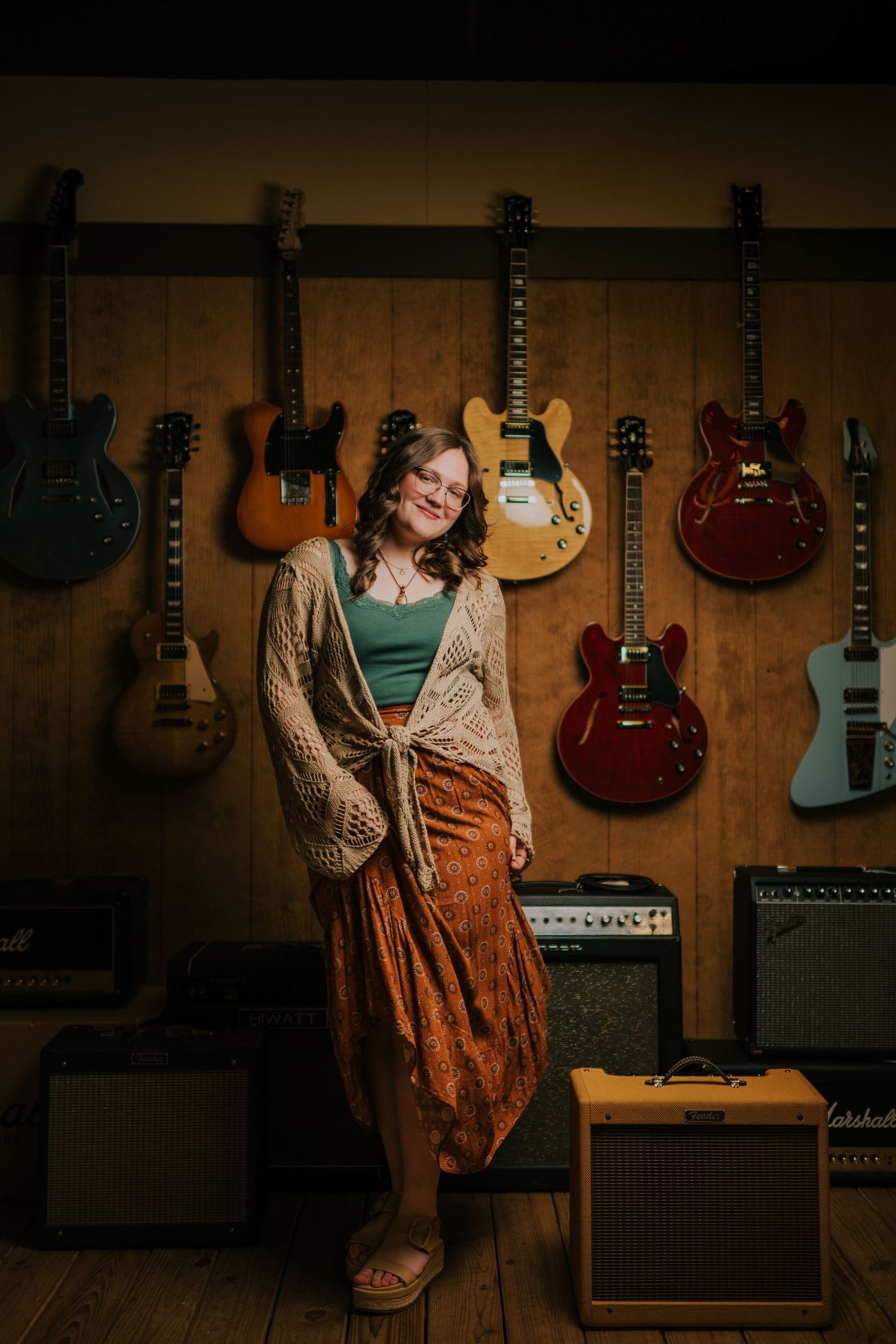 Collection of electric guitars displayed on wall with vintage amplifier and music equipment.