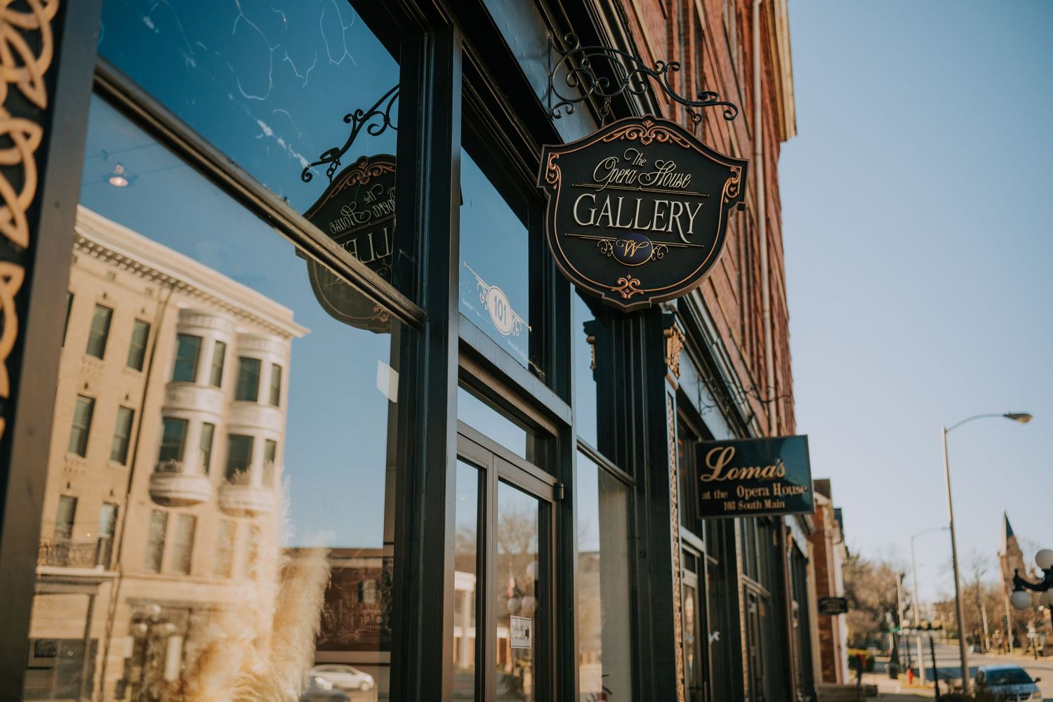 View of a vintage gallery storefront sign and window on a brick building in an urban downtown setting.