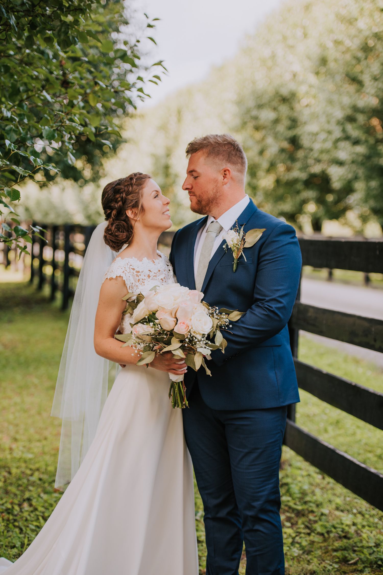 A tender moment between newlyweds in a garden setting with black fencing.