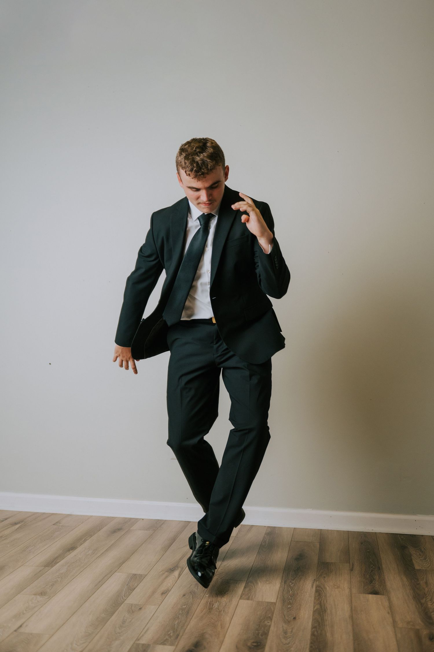 Dynamic dance poses in business suit against white studio backdrop.