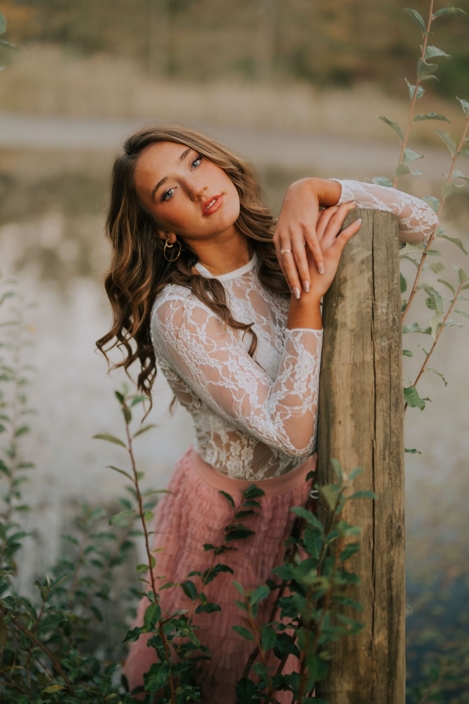 A dreamy portrait session featuring a woman in lace posing against a rustic wooden fence.