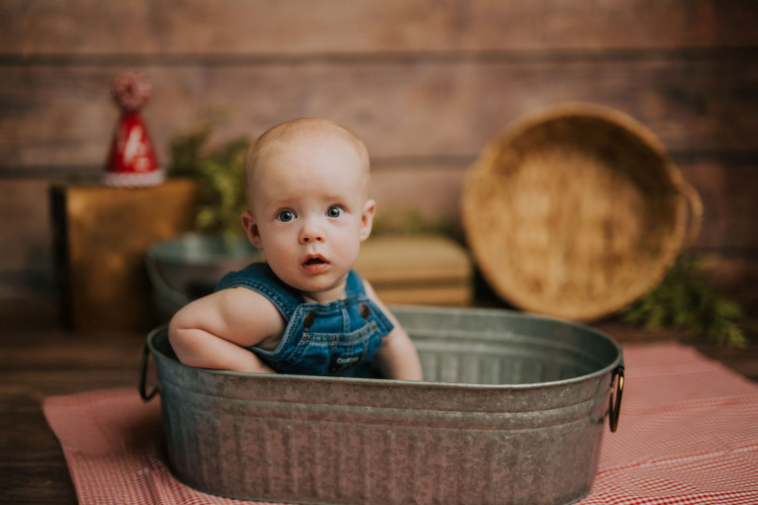 Baby sitting in vintage metal wash tub during rustic photo session.