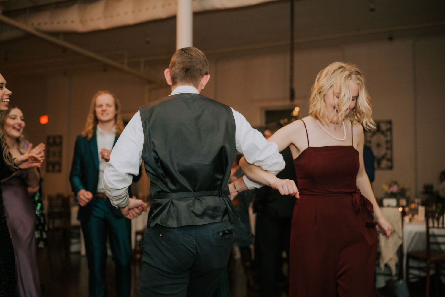 Wedding guests dancing on the dance floor at evening reception celebration.