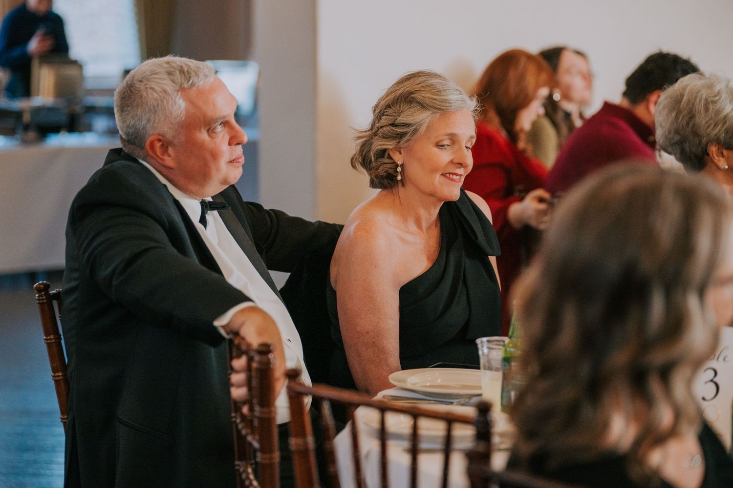 Formal evening event guests seated at round tables in an elegant ballroom setting.