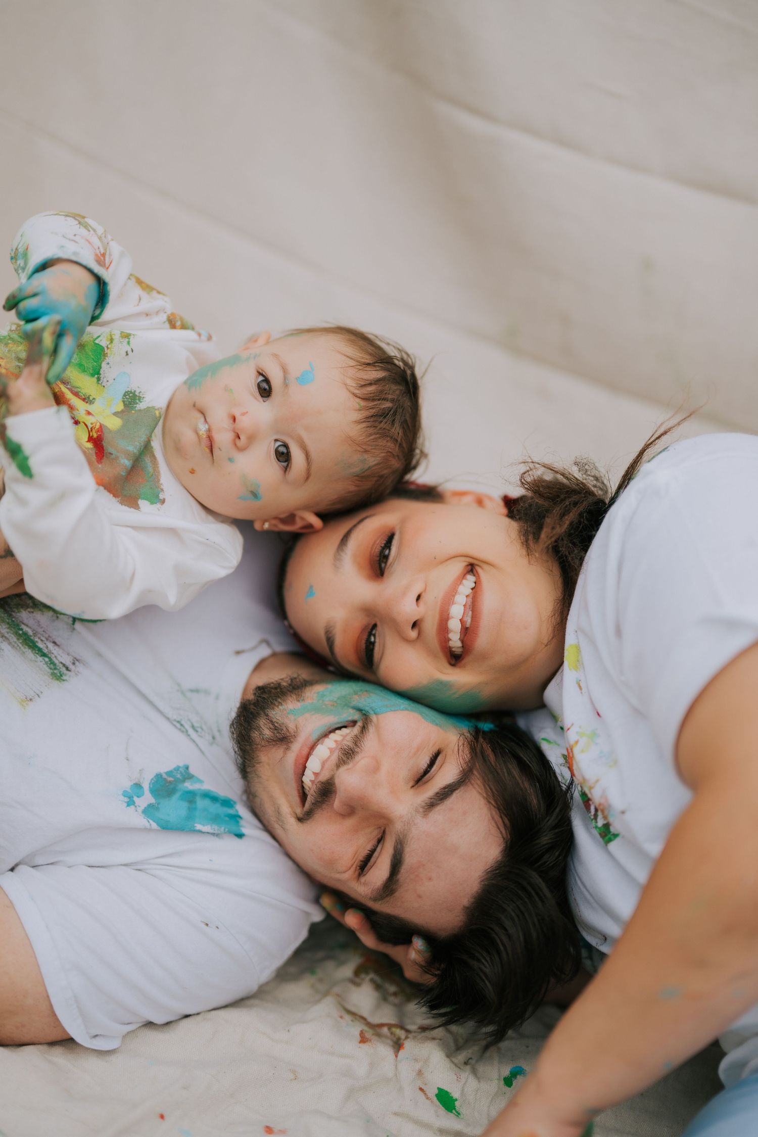 People lying down wearing white shirts with paint splattered on them during a creative photoshoot.