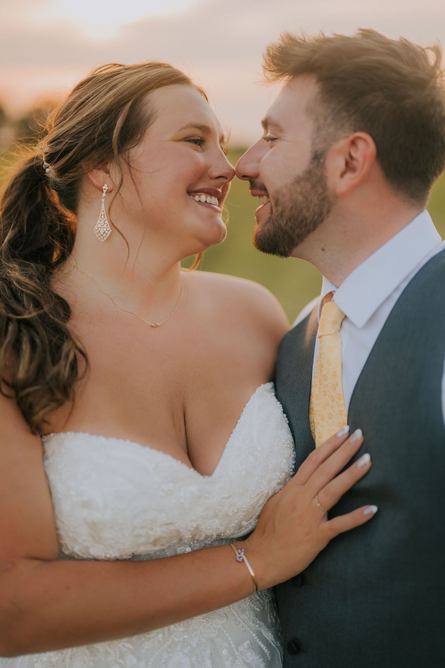 Romantic close-up wedding portrait against a warm sunset backdrop.