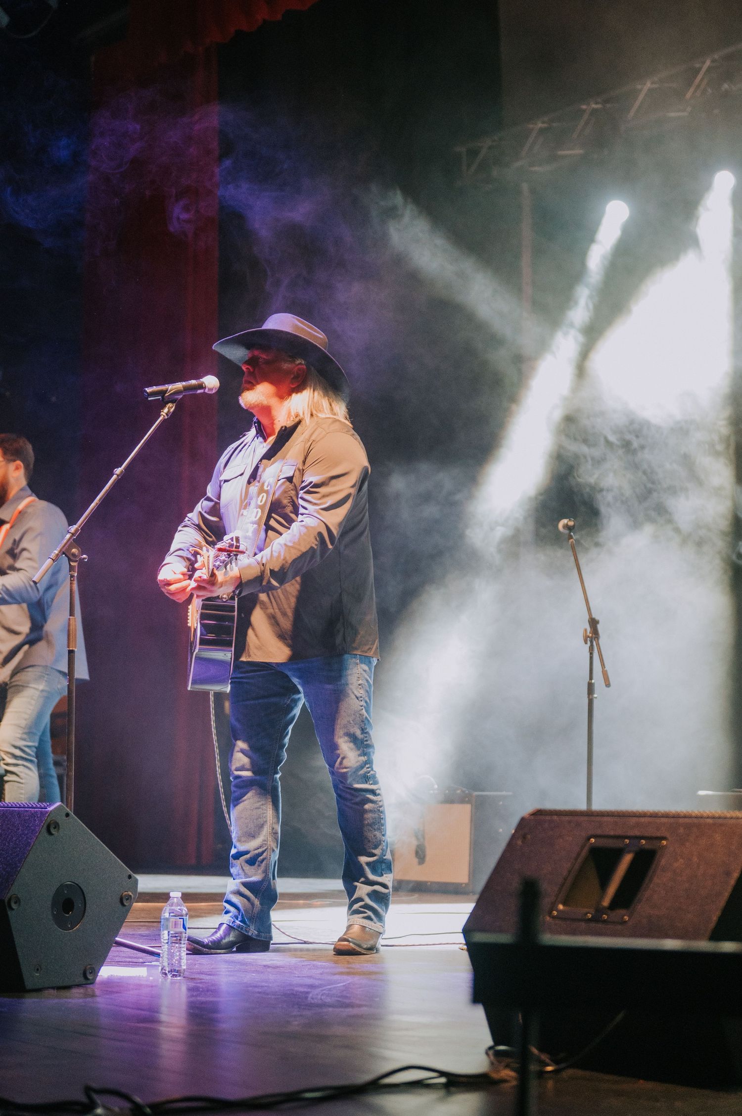 Country music performance on stage with dramatic lighting effects and smoke during a live concert.