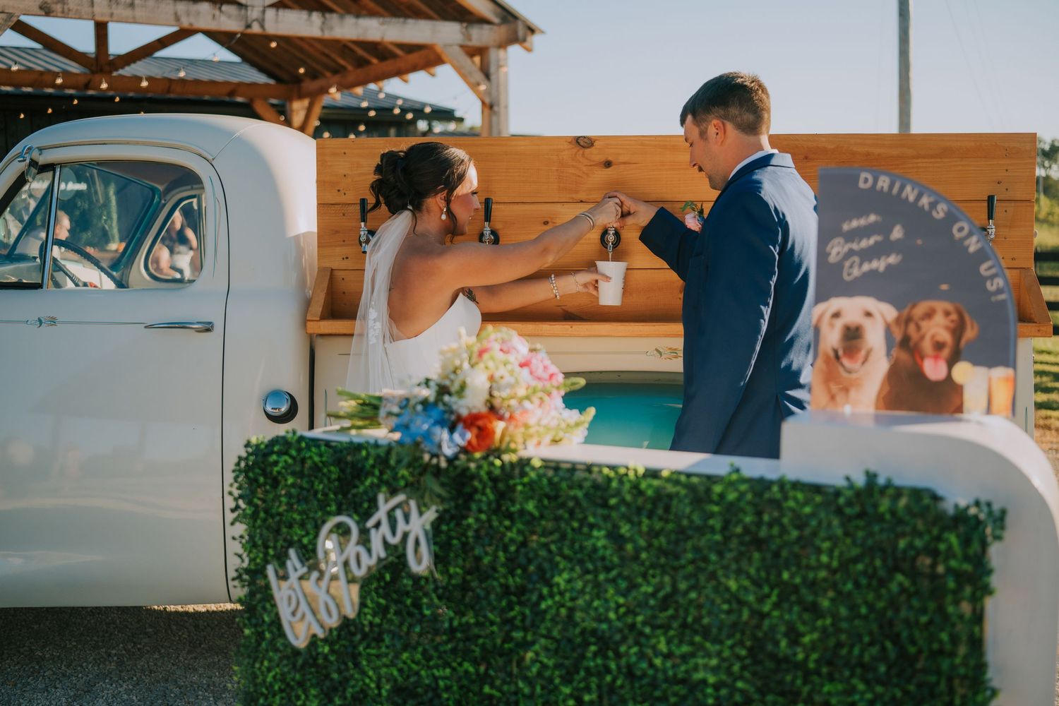 Wedding reception setup with rustic wooden decor and floral arrangements at sunset.
