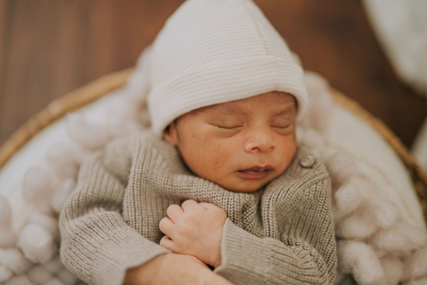 Peaceful newborn baby sleeping while wearing soft knit sweater and hat.