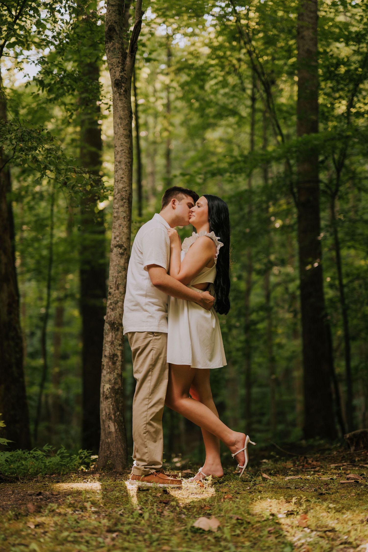 Romantic forest photoshoot with couple among tall trees.