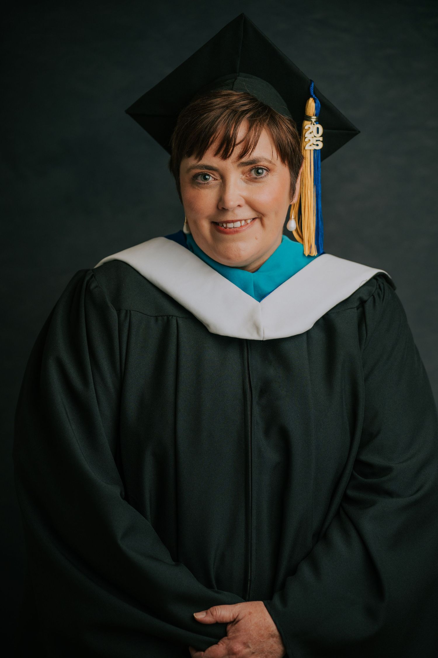 Academic graduation portrait showing traditional black gown with white collar and gold tassel.