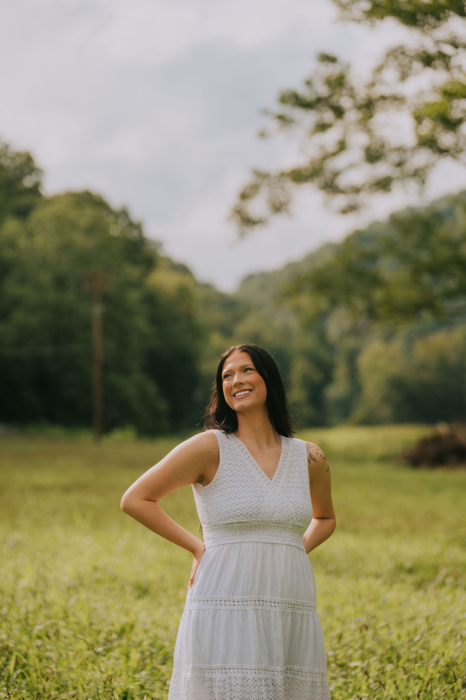 A joyful moment captured in a sunlit meadow wearing a flowing white dress.
