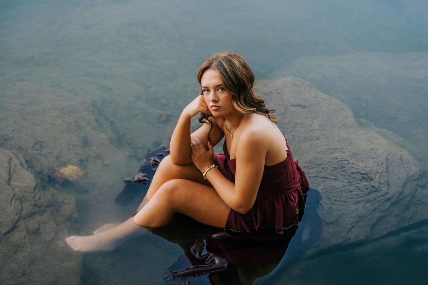 Serene lakeside photography series featuring burgundy dress against water backdrop.
