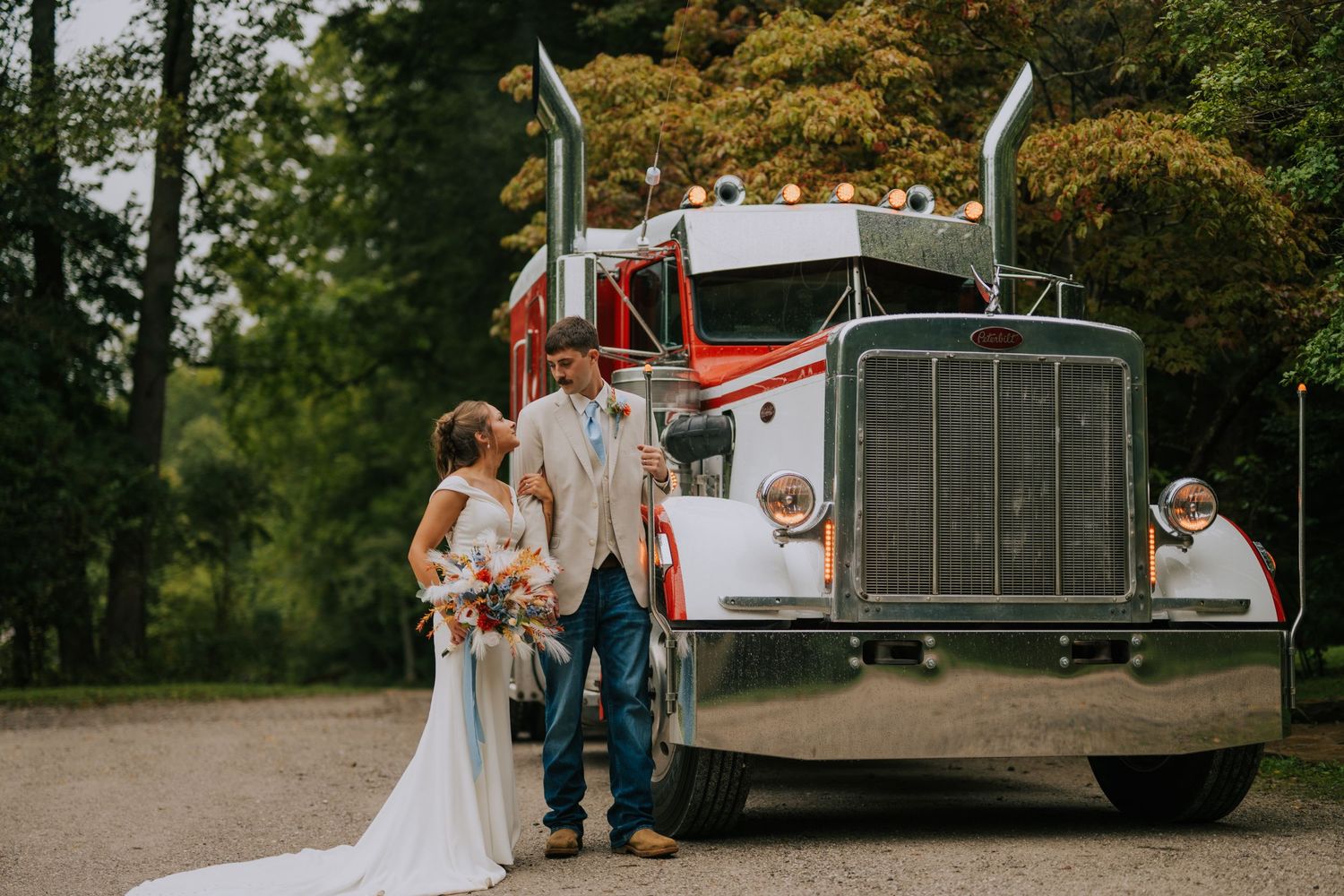 A vintage white truck serves as a backdrop for wedding photos in a park setting.