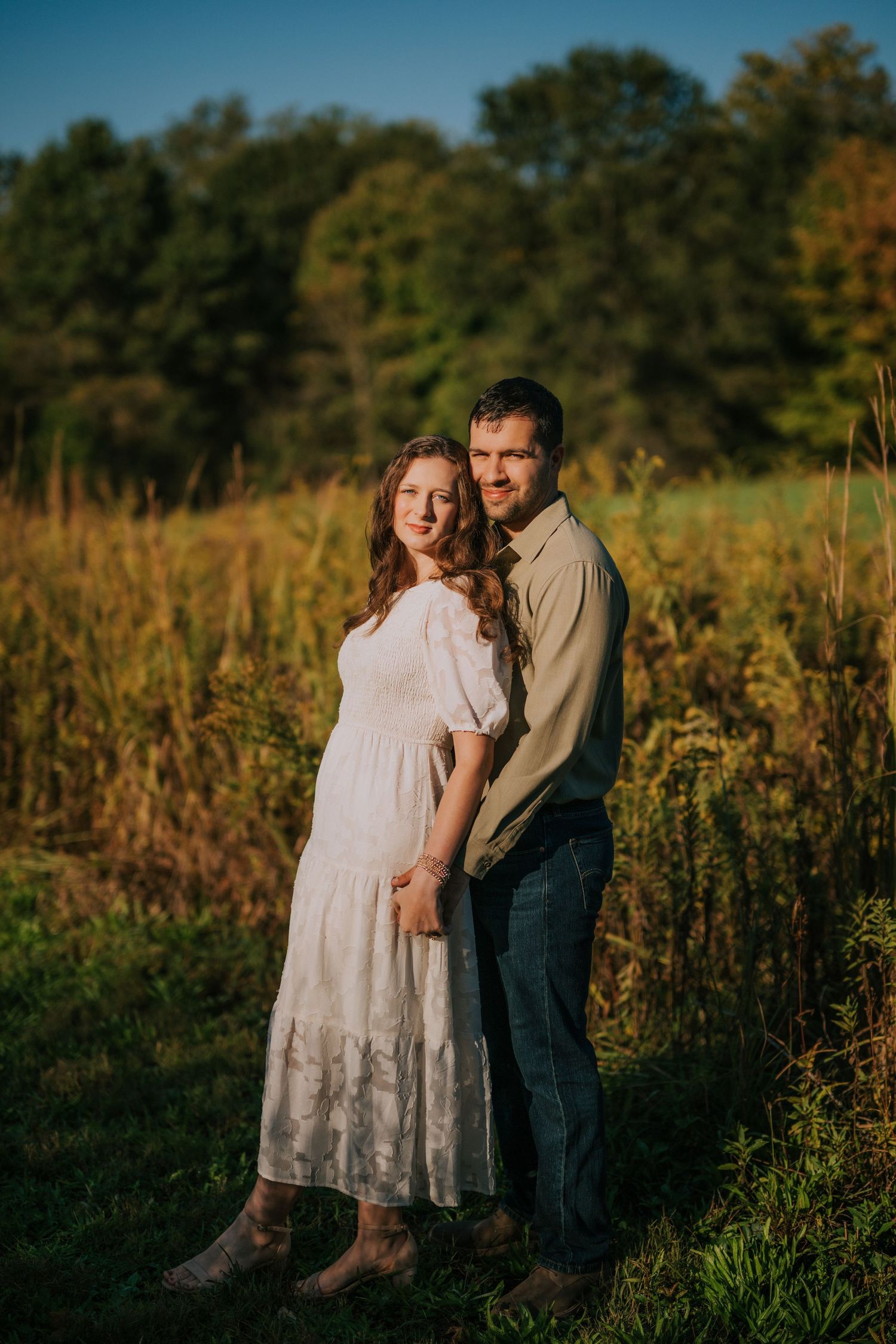 A romantic sunset photoshoot in a field with tall grass and natural lighting.