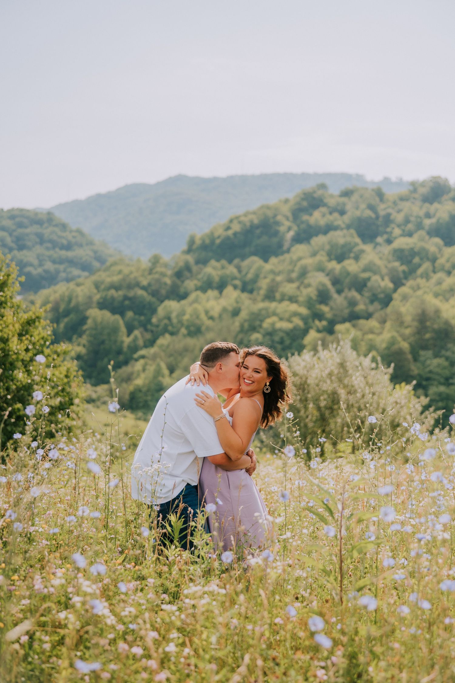 A romantic moment captured in a wildflower meadow with mountain views.