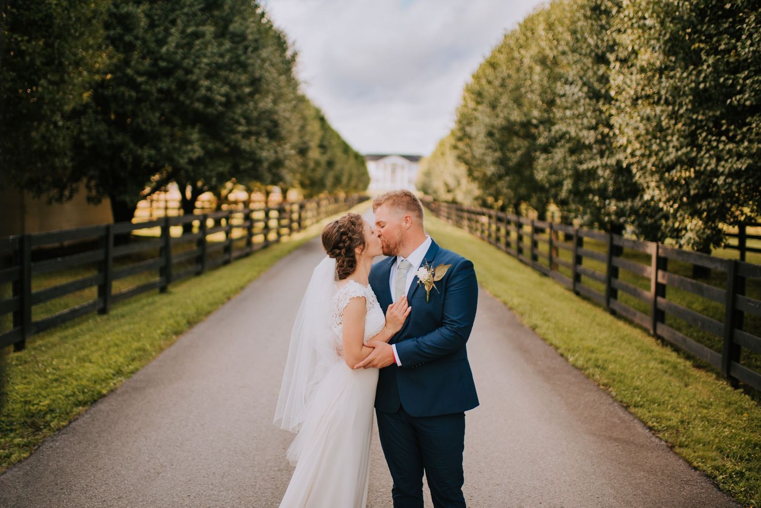 A wedding couple walks along a tree-lined path on their special day.